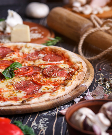 Tender pizza with sausage, tomatoes and cheese. Pizza on a black background. As package design elementの写真素材