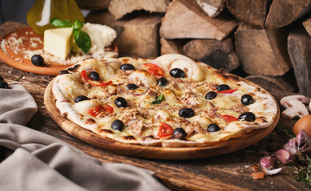 Pizza with fish and olives among ingredients for its preparation. As package design element. Pizza on a wooden backgroundの写真素材