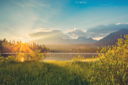 Mountain Lake in the High Tatras National Park. Strbske Pleso, Slovakia. Amazing views of the mountains and lakes in the rays of the sunrise.の写真素材