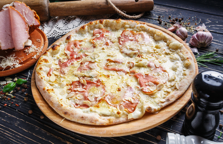 Aromatic pizza on a wooden board. Mockup. Concept promotional flyer. Pizza on a black backgroundの写真素材