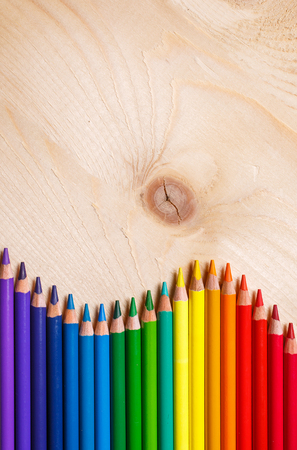 Pencils in rainbow color wave laid on wooden background. Top view, flat lay. copyspaceの写真素材