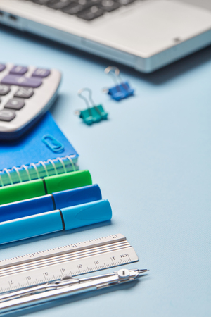 A notebook next to a school stationery on a blue background. Working place elementsの写真素材