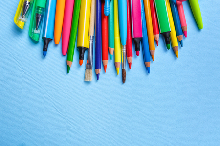 Colored pens, pencils, markers and other objects lie on a light blue background. Concept of education or back to school. Top view, flat lay. copyspace