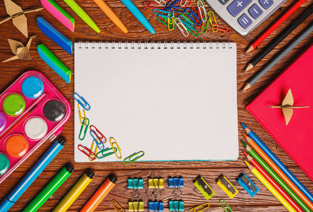 Bright stationery is laid out around the notebook. On a wooden background. Top view, flat lay. copyspaceの写真素材