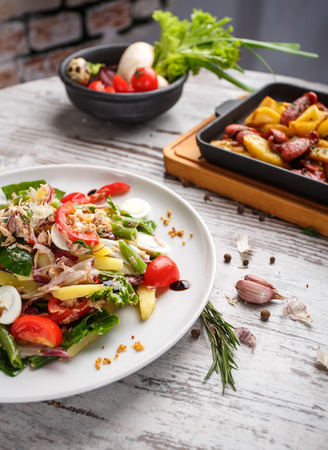 The composition on the table resembles home comfort. Salad of quail eggs, beans in pods, tomatoes, onions and other ingredients. On a light backgroundの写真素材