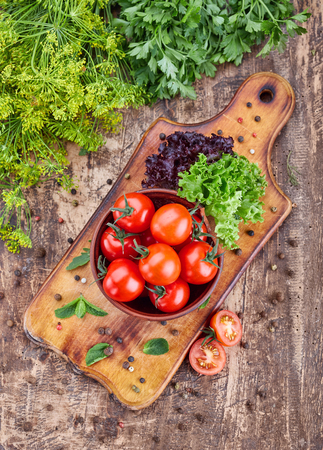 A plate of fragrant tomatoes on a wooden board with mint. Top viewの写真素材