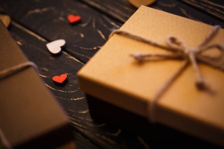 Decorated hearts on a dark textured wooden background. Brown gift boxes with bow. Selected focus, Hearts in focusの写真素材
