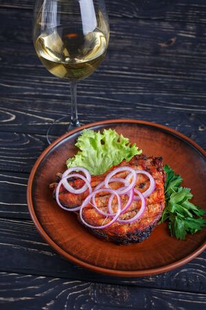 Juicy steak with onions, lettuce and parsley on the plate. Meal from the menu of the restaurant. A glass of white semi-sweet wineの写真素材