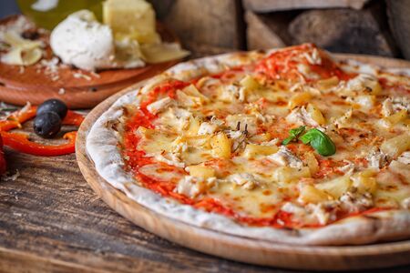Exquisite pizza with chicken and pineapple, near with olives. Pizza on a wooden background. As package design elementの写真素材