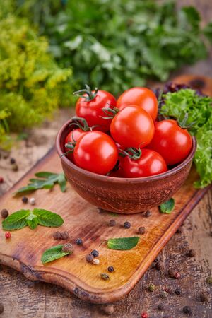 A plate of fragrant tomatoes on a wooden board with mint. On a wooden backgroundの写真素材