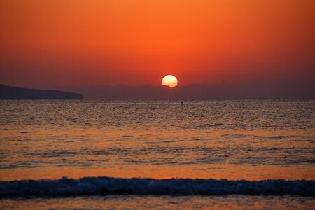 Beautiful sunset landscape at black sea and orange sky above it with awesome sun golden reflection on calm waves. Amazing summer sunset view on the beach.の写真素材