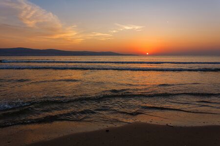 The sun sits behind the horizon. Summer landscape. Warm evening on the seashore. Vacations and travel concepts.の写真素材