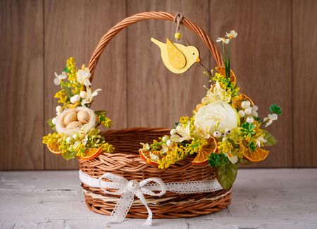 Decorative basket decorated with flowers on wooden boardの写真素材