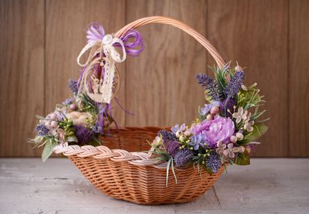 Beautiful decorative basket with flowers to celebrate Easter on a wooden backgroundの写真素材