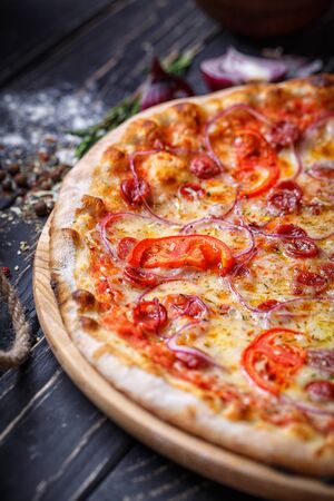 Aromatic pizza with hunting sausages, onions and tomatoes. Pizza on a black background. As package design elementの写真素材
