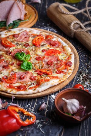 Composition of sausage pizza and ingredients for its preparation. Concept promotional flyer. Pizza on a black backgroundの写真素材
