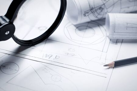 Magnifier for work with small details of the engineering drawing. architectural background with rolls of technical drawings and blueprints. selective focusの写真素材