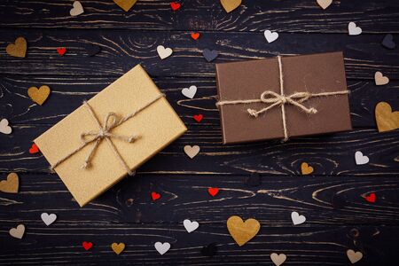 Two brown gift boxes on a wooden background with a bow of a simple rope on wood backgraund. Small decorative wooden hearts near boxの写真素材