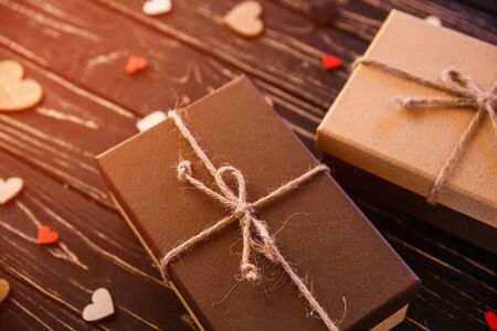 Two brown gift boxes on a wooden background with a bow of a simple rope on wood backgraund. Small decorative wooden hearts near boxの写真素材