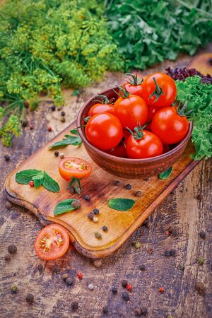 A plate of fragrant tomatoes on a wooden board with mint. Fresh vegetables on the tableの写真素材