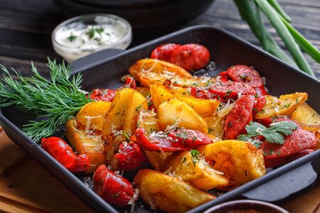 Poster for Restaurants. Potato baked with sausages and decorated with herbs. On a black wooden backgroundの写真素材