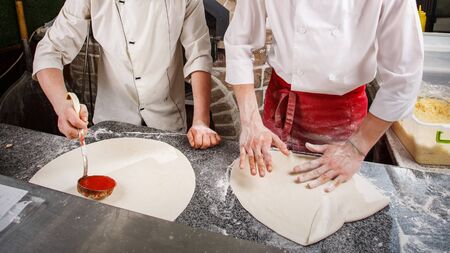Two chefs for the magic of creating pizza. Cooking pizza in the cafe.の写真素材