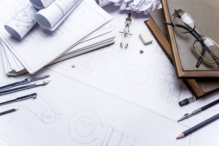 Books, glasses, pencil, compass and rolls of drawings on the details of industrial drawings. The set of elements reflecting the concept of engineering and design.の写真素材
