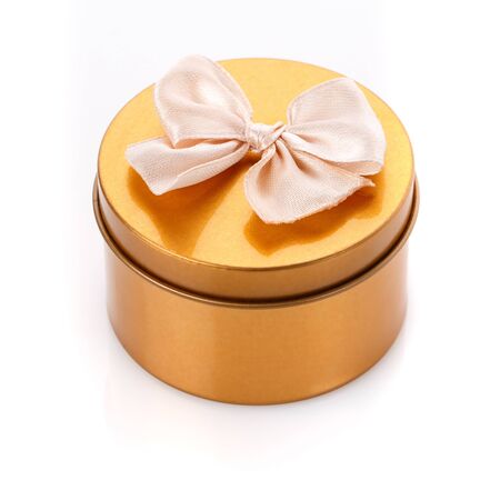 Single round gold gift box with bow on white background. Modern present for any holiday, christmas, valentine or birthdayの写真素材