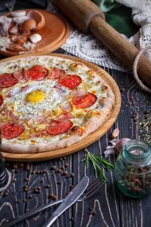 Aromatic pizza with egg and sausage. A fragment of pizza. Concept promotional flyer. Pizza on a black backgroundの写真素材