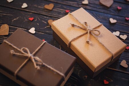 Two brown gift boxes on a wooden background with a bow of a simple rope on wood backgraund. Small decorative wooden hearts near boxの写真素材