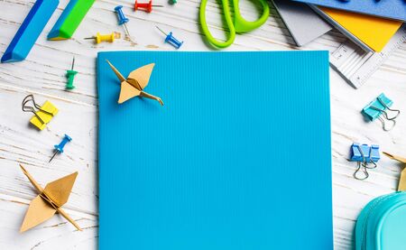 A blue notebook is lying on a white table next to a bright stationery. Flat lay, place for text. Top viewの写真素材