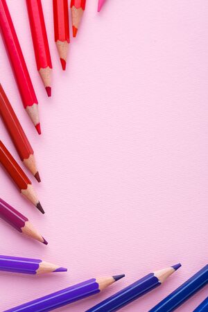 A group of bright wooden pencils on a pink background. Bright color palette of crayons on the table. Top view, flat lay. copyspaceの写真素材