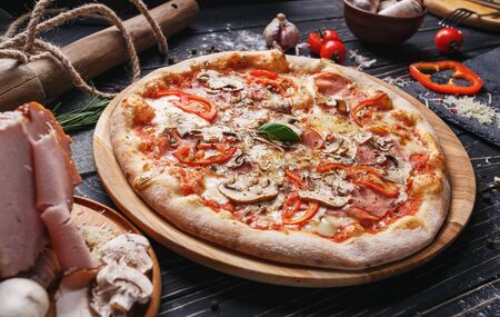 A composition of mushroom pizza and ingredients for its preparation. Pizza on a black background. As package design elementの写真素材