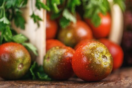 Vegetables in the basket on the table. Composition with vegetables. Tomatoes in dewの写真素材
