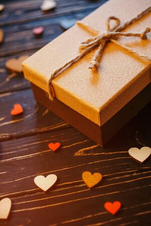 Decorative wooden hearts and a gift box on a dark textured wooden table. Love, celebration and gift concept.の写真素材