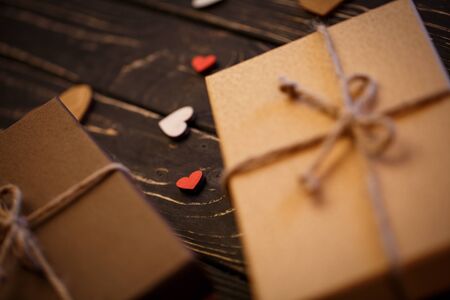 Decorated hearts on a dark textured wooden background. Brown gift boxes with bow. Selective focus, Hearts in focus. Greeting concept backgroundの写真素材