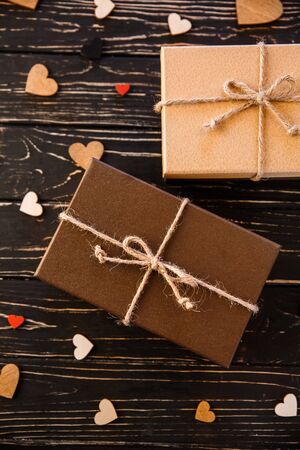 Two brown gift boxes on a wooden background with a bow of a simple rope on wood backgraund. Small decorative wooden hearts near boxの写真素材