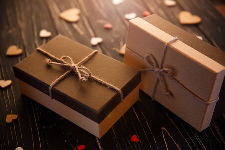 Two brown gift boxes on a wooden background with a simple bow of a cord.の写真素材
