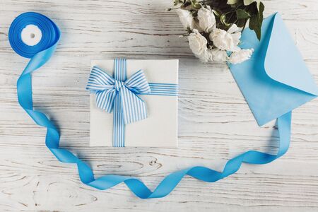 Gift box with bow. Blue satin ribbons, letter and flowers decor. Top view, flat lay. Mother's day. Women's day. Valentine's day, Birthday greeting concept background.の写真素材