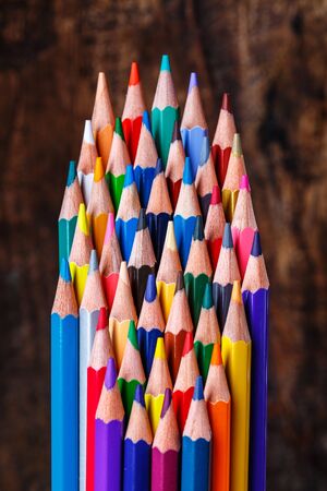 A group of bright wooden pencils on a wooden background. Colorful art studying and painting process. Drawing with pencils.の写真素材