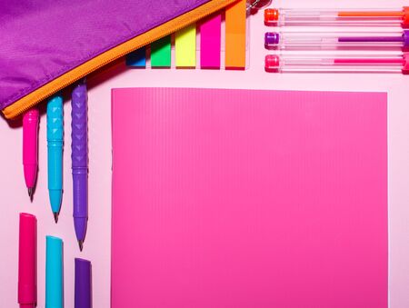 On the pink table there is: a pink notebook, purple pencil case, color pens and bright stickers. Flat lay, top view. place for textの写真素材