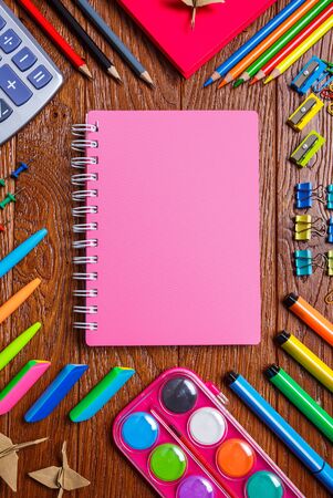 The background for your postcard is back to school. Bright stationery is laid out around the notebook. On a wooden background. Top view, flat lay.の写真素材