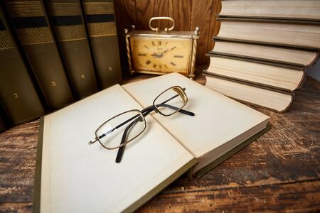 An open book in a library on a wooden table. Working place elementsの写真素材