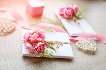 White paper wrapped gift box with rope bow on a rustic wood background. Floral decor elements.の写真素材
