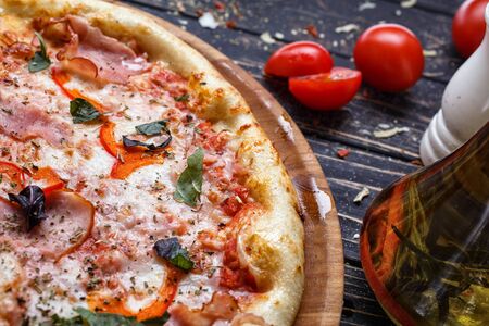 Pizza with ham, mozzarella, pepper, spices and fresh basil. Italian pizza. Restaurant food. Tasty meal concept . Rustic wooden backgroundの写真素材
