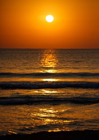 Beautiful sunset landscape at black sea and orange sky above it with awesome sun golden reflection on calm waves. Amazing summer sunset view on the beach.の写真素材