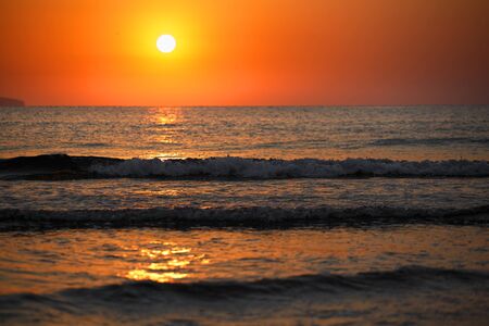 Beautiful sunset landscape at black sea and orange sky above it with awesome sun golden reflection on calm waves. Amazing summer sunset view on the beach.の写真素材