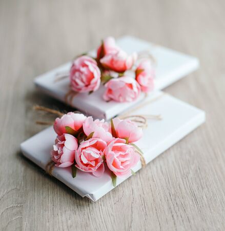 Couple of gift boxes wrapped with simple white craft paper and decorated with bouquet of roses and bunch of eucalyptus. Rustic decor.の写真素材
