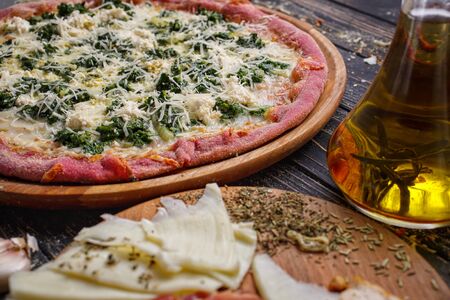 Cheese pizza with herbs. Unconventional Pink Pink Dough. Pizza menu. Close up of fresh baked pepperoni pizza. Delicious italian pizza served on wooden tableの写真素材