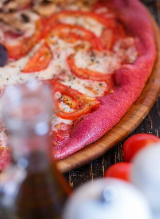Unusual pizza from pink dough. not traditional cuisine. Innovative pizza. Macro photo. Pizza with cheese and tomatoesの写真素材
